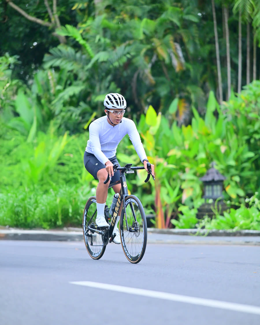 Riding a road bike on a tree-lined road in Bali