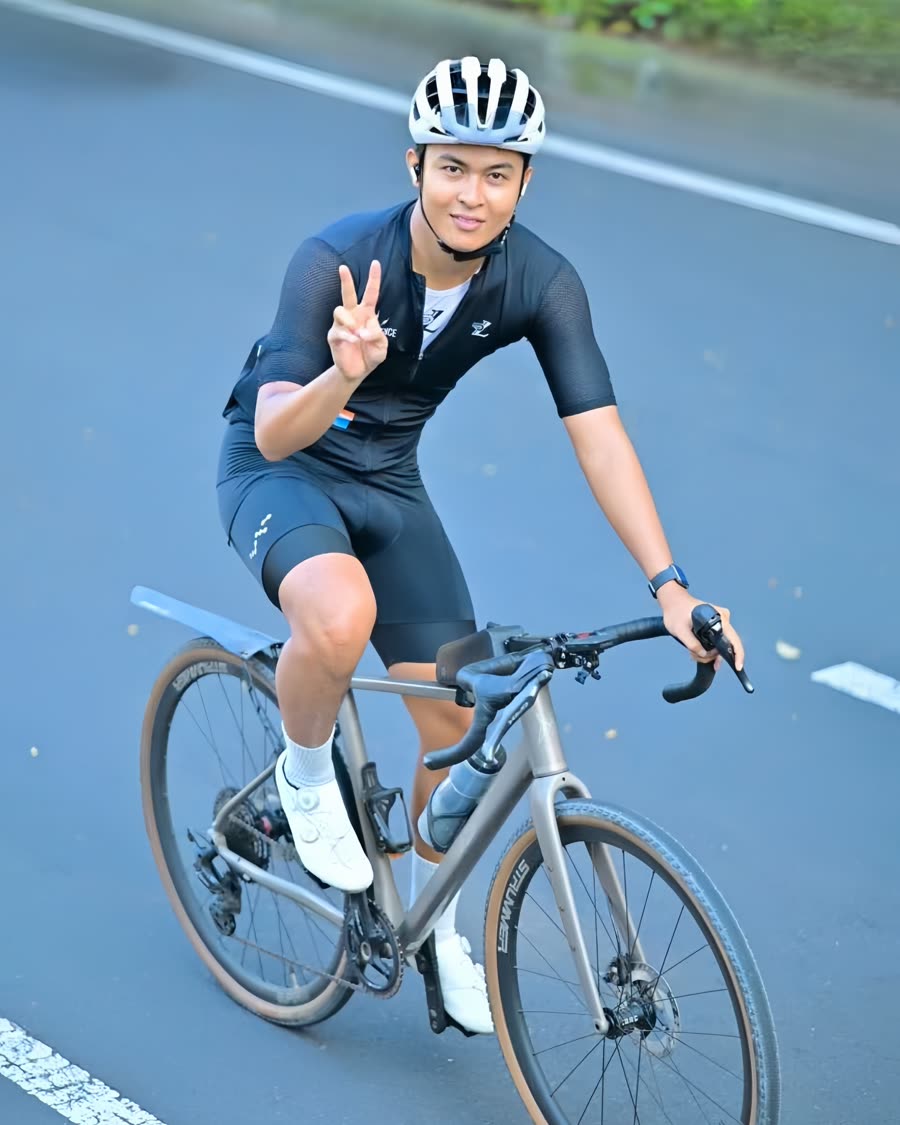 On a gravel bike, throwing a peace sign at the camera